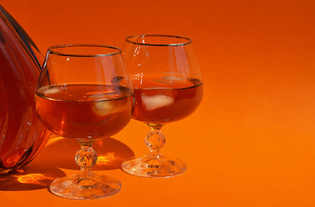 Two glasses of cognac on an orange background. close-upの写真素材