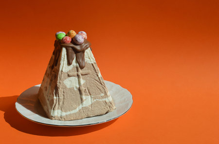 Cake with chocolate cream and candies on a plate on an orange backgroundの写真素材