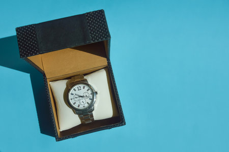 Wrist watch in a gift box on a blue background with shadowの写真素材