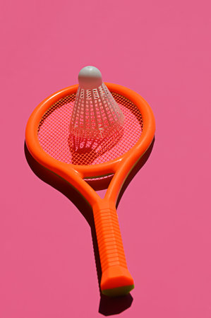 Orange badminton racket and shuttlecock isolated on pink background.の写真素材