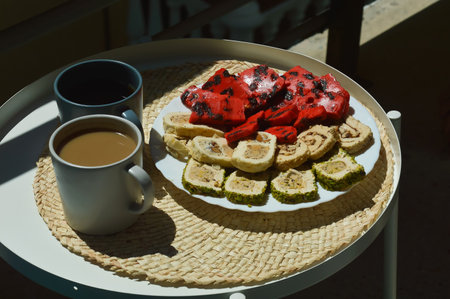 A cup of coffee and a plate of oriental sweets on the tableの写真素材