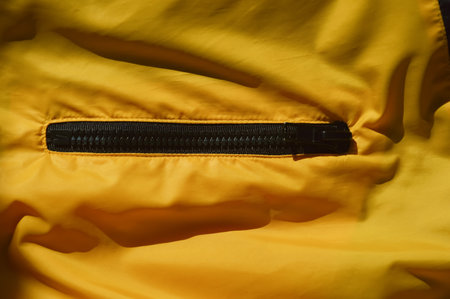 Close up of a yellow raincoat with a zipper on it.