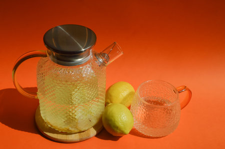 Lemonade in a glass teapot on an orange backgroundの写真素材
