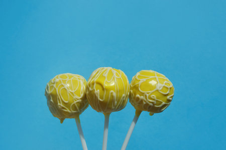 Cake pops with yellow glaze on blue background, copy spaceの写真素材