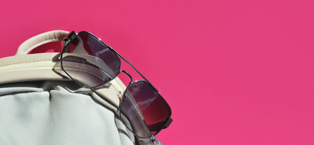 Sunglasses and backpack on a pink background with copy space.の写真素材