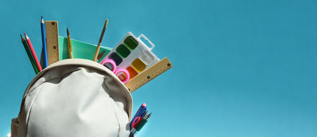 School supplies in a backpack on a blue background. Back to school concept