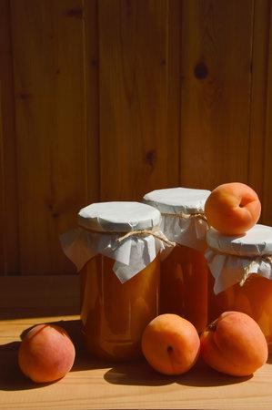 Homemade apricot jam in glass jars on a wooden backgroundの写真素材
