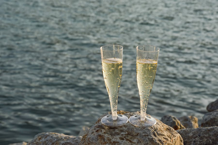 Two glasses of champagne on the rocks near the sea, close-upの写真素材