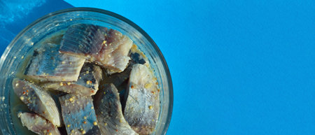 Pieces of salted herring in a glass bowl on a blue backgroundの写真素材