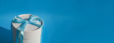 White gift box with blue ribbon on a blue background. Place for text.の写真素材
