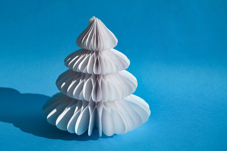 White Christmas tree made of paper on a blue background. Minimal concept.の写真素材