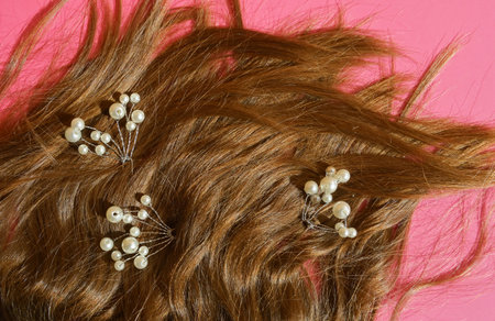 Curly hair with pearls on pink background. Top view.の写真素材