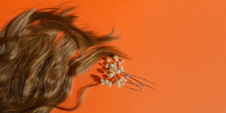 Curly hair with flowers on orange background. Flat lay, top view.の写真素材