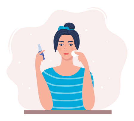 Young woman cleaning her face with cotton pad, holding cleaning lotion in her hand. Beauty, skin care and cosmetic concept. Vector illustration in flat styleのイラスト素材