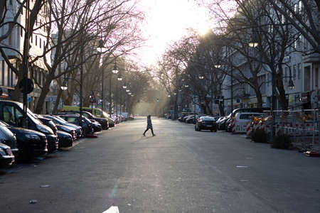 Berlin / Germany - 01 05 2020: Silhouette Of Man Crossing empty Street At Sunset