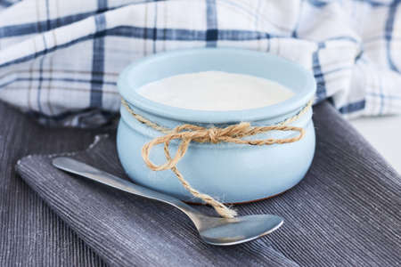 Greek yogurt in a ceramik blue bowl with a spoon on a gray napkin, rustic styleの写真素材