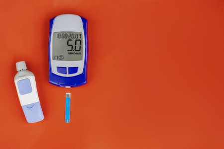 Digital glucometer and lancet pen on yellow background, close-up, flat lay. Diabetes concept. Blood glucose meter.の写真素材