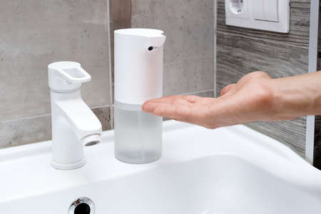 Close up of a man using automatic contactless soap dispenser