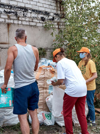 Russia, Nizhny Novgorod - 08 29 2020: Volunteer ecological action for separate waste collection. Volunteer stands next to a huge bag full of plastic bottles, helping people to sort plastic wasteのeditorial素材