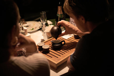 Nizhniy Novgorod Russia-09/05/2020: Chinese Tea Ceremony. Caucasian man is pouring Natural Tea In The Dark Room With A Wooden stand sitting at restaurant in the eveningのeditorial素材