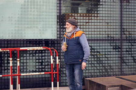 Berlin Germany-03.01.2020: Senior man with beard smokes a cigarette and drinks beer, thoughtful...