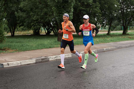 Russia-08.08.2020: Two enduring strong concentrated young men runs a marathon