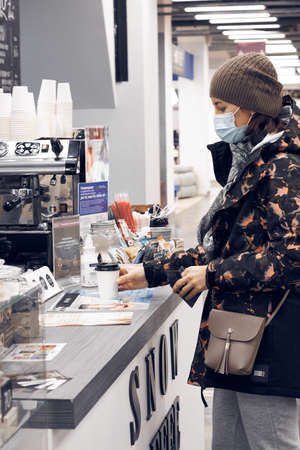 Nizhny Novgorod Russia-12.12.2020: A woman in medical mask buys coffee in a Coffee shopのeditorial素材