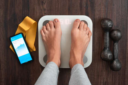 Top View Of a Person Standing On a Smart Weighing Scale, a smartphone connected to the Scale and Fitness equipment. Smart technology and health care conceptの写真素材