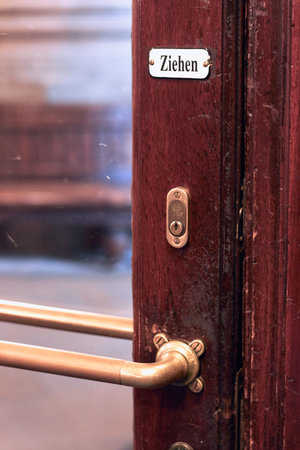 Close-up of an old vintage wooden door with gold metal lock and doorknob with written word ziehen, translates as pull in Germanの写真素材