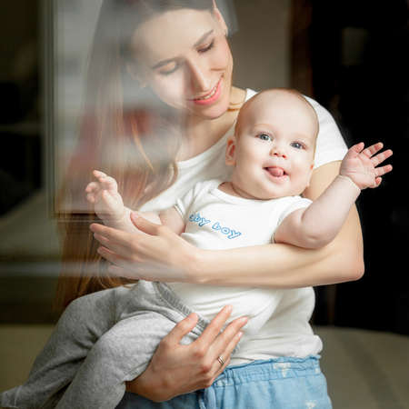 Mom plays with the baby 6 months on the bed at home