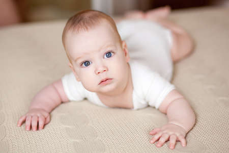 Cute beautiful baby with big eyes lies on the bed