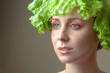 Surprised model girl with Lettuce hair style. Beautiful happy young woman with green vegetables on her head. Healthy food concept, diet, vegetarian food. Dieting concept. Weight loss. Vegan foodの写真素材