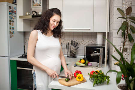 pregnant woman using a tablet computer in her kitchenの写真素材