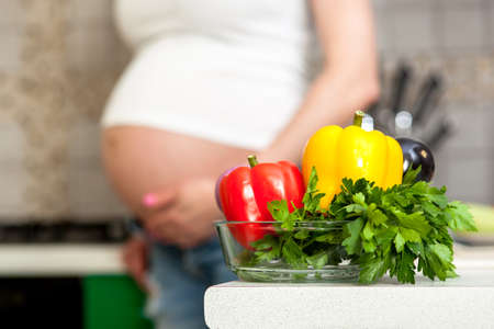 pregnant woman using a tablet computer in her kitchenの写真素材