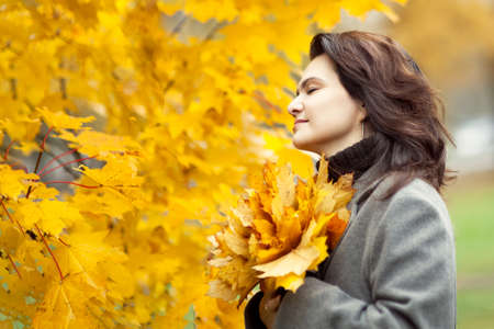 Beautiful elegant woman in autumn park. Fall yellow garden backgroundの写真素材