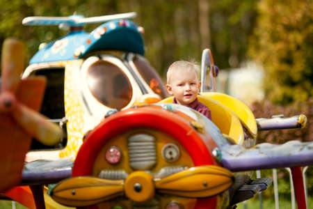 beautiful blond boy having fun on the amusement rides at the amusement Parkの写真素材