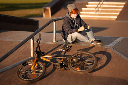 girl sits on the bike stand on the asphalt in the helmet on the sunset