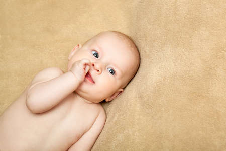 Smiling baby boy on beige background.