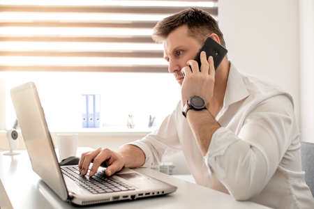 Caucasian male working from home office and talking on the phone