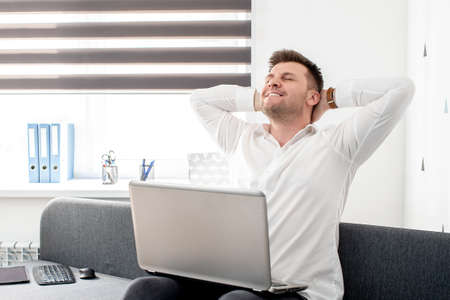Handsome businessman is using a laptop while sitting on couch at home