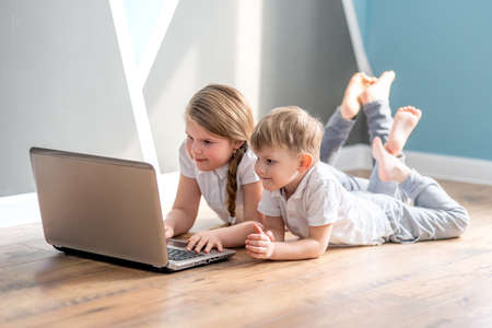 Schoolboy and girl studying at home with digital laptop notebook and doing school homework. Distance...