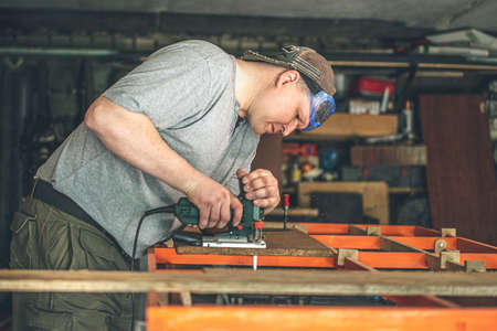 Carpenter sawing wood with an electric jigsaw. small businessの写真素材