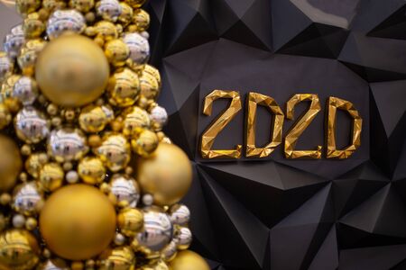 Christmas tree made of golden ball in the foreground. on the foreground, the number 2020 on a dark background.の写真素材