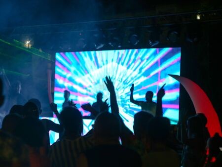 Blurred people standing back. Big screen with music. Disco near the hotel. Entertainment at the...