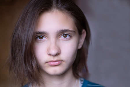 Close-up of the face of a beautiful young brunette girl with dark brown eyes.