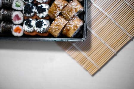 Close-up of sushi, rolls in container. There is a mat for making sushi nearby. Making sushi at home....