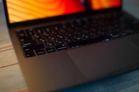 Close-up of macbook laptop keyboard, wooden table. Laptop for work and study. Modern high-speed laptop. Touchpad of a gray MacBook. Orange picture on the macbook screen. Minsk Belarus, December, 2021のeditorial素材