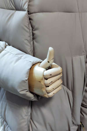 The wooden hand of a doll, mannequin shows super gesture, a thumbs up. A mannequin in a warm jacket....