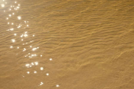 Yellow sand in the shallow waters of the sea. Small dunes on the sand under clear light water. The...