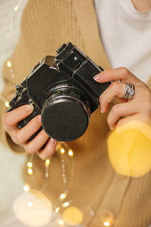 Close-up of a woman holding a retro camera and a garlandの写真素材
